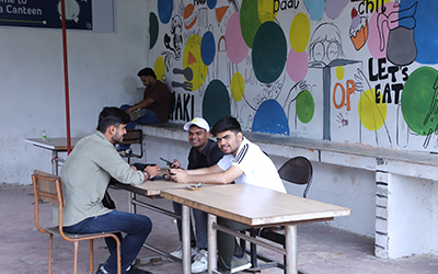Three students sitting in the canteen at IMS Noida, enjoying their time together and having a conversation.